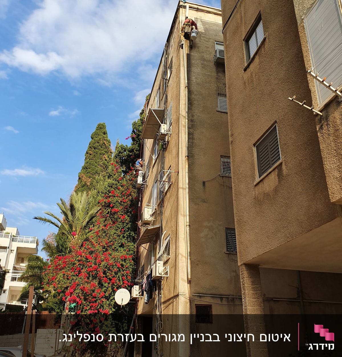 עובד בגובה על בניין עם ציוד בטיחות